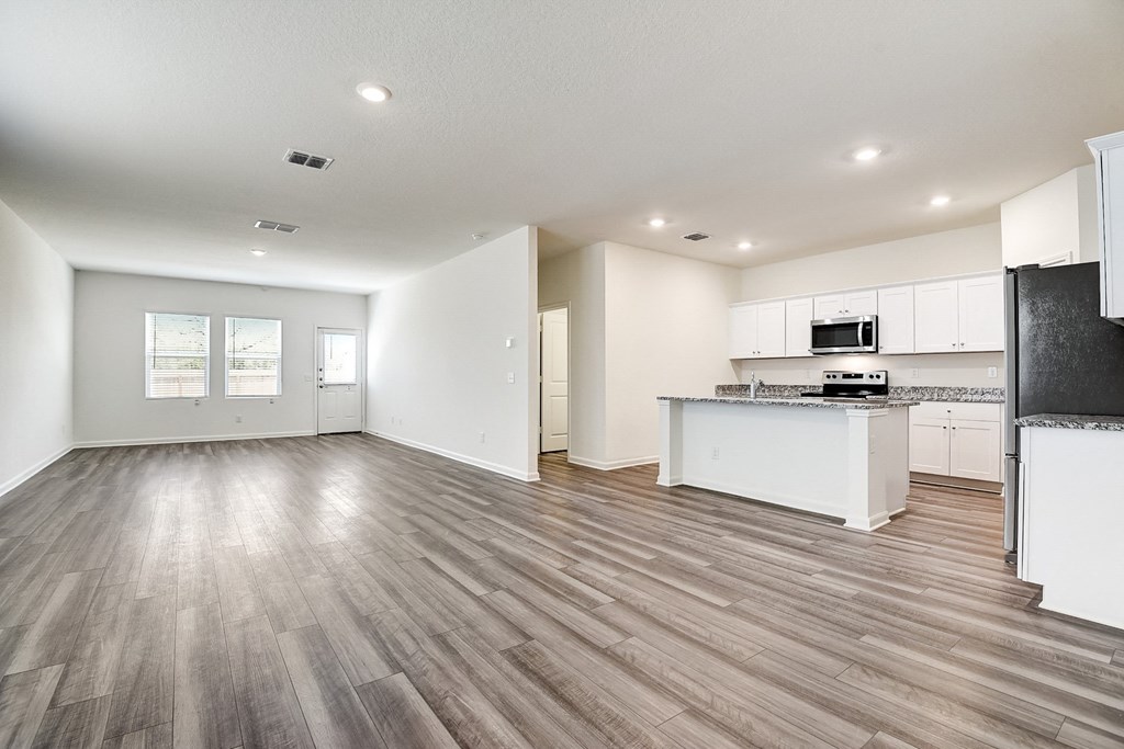 a kitchen and living room with hardwood floors and white walls at Beacon at Meridian, San Antonio Texas