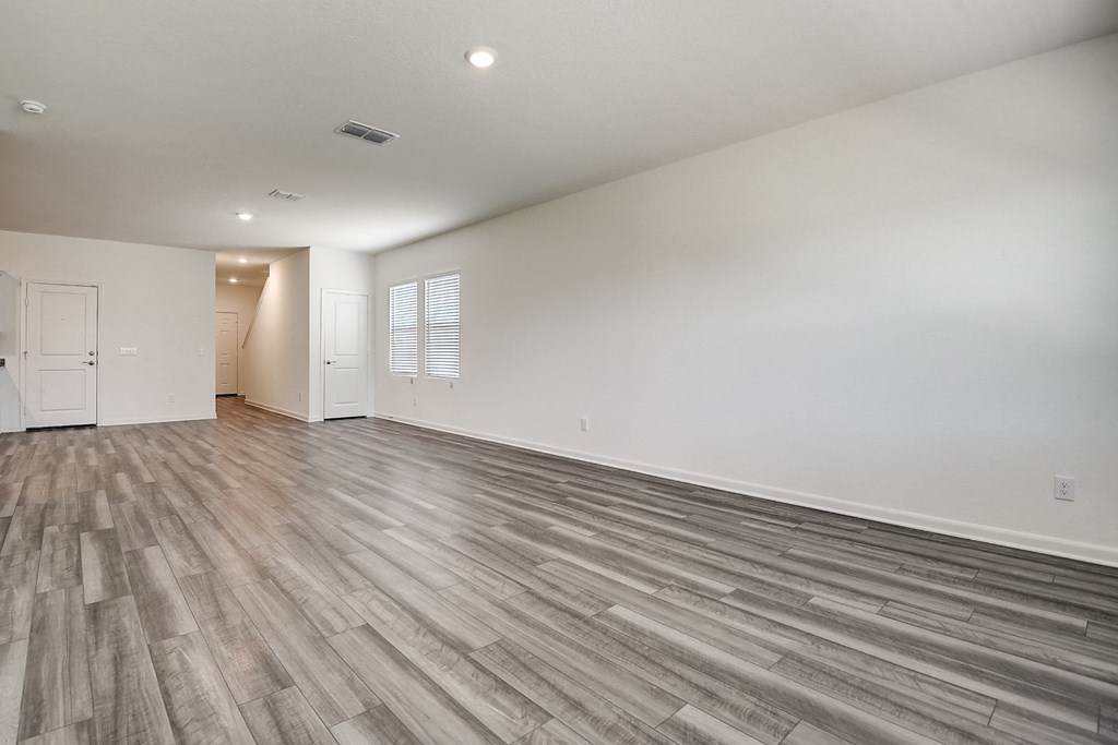 a living room with windows, hardwood floors and white walls