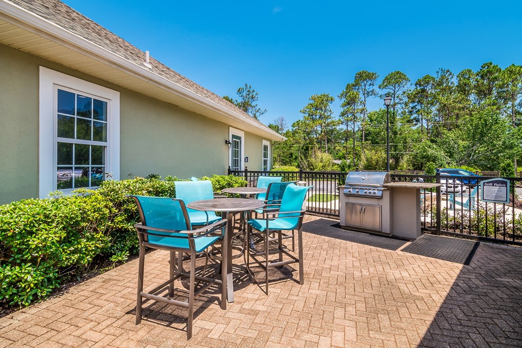 a patio with a table and chairs and a grill