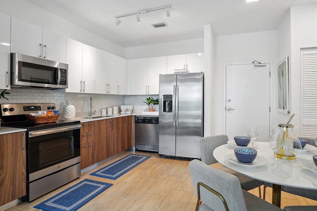 a kitchen with white cabinets and stainless steel appliances and a white table and chairs