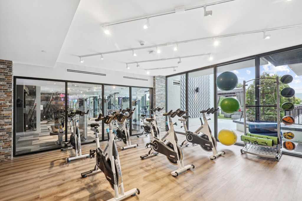 a gym with a variety of exercise equipment and large windows