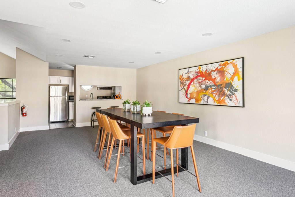 Clubhouse dining area with tall table and seats next to kitchen at Bandera Crossing apartments in San Antonio, TX
