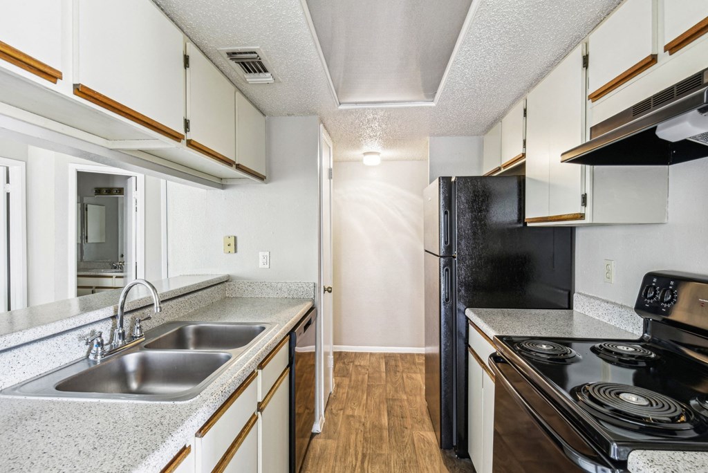 Modern kitchen with black appliances and double basin sink at Bandera Crossing apartments in San Antonio, TX