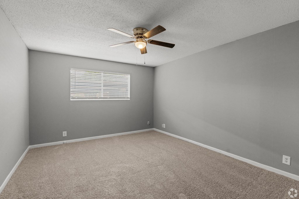Looking into vacant bedroom with a ceiling fan and windows letting natural light in at Bayou Oaks Apartment Homes in Alexandria, LA
