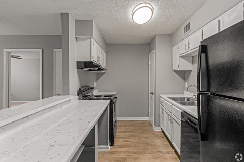 A kitchen with a black refrigerator and white countertops.