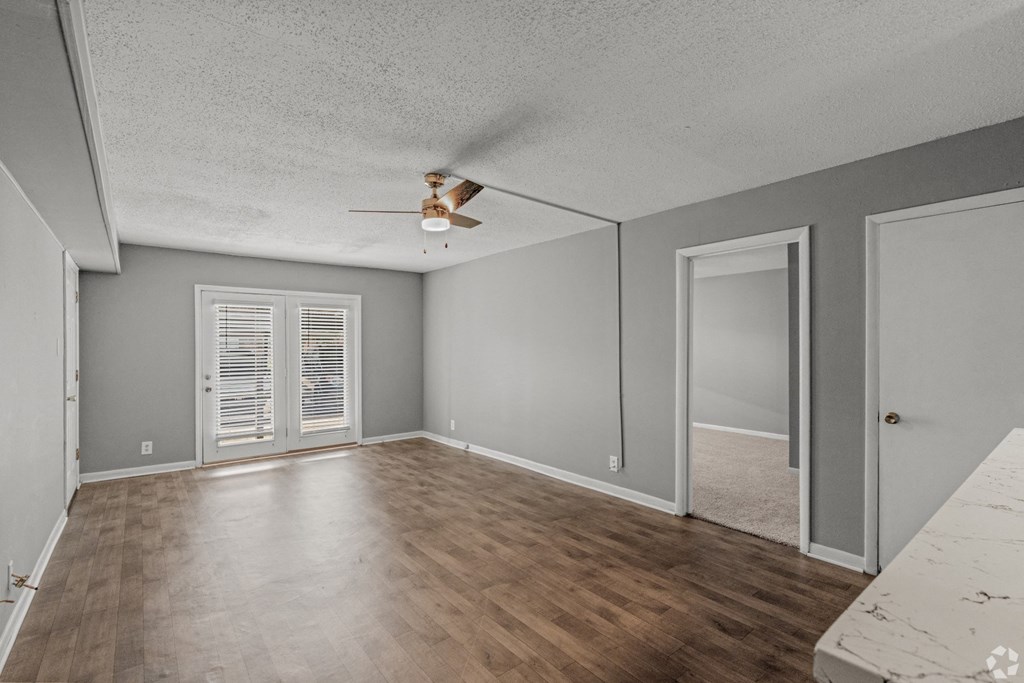 Apartment living room with wood-like floors and a ceiling fan at Bayou Oaks Apartment Homes in Alexandria, LA
