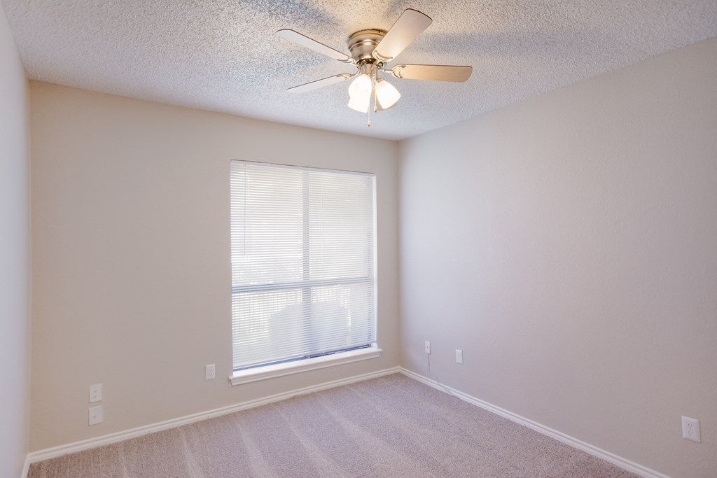 an empty living room with a ceiling fan and a large window