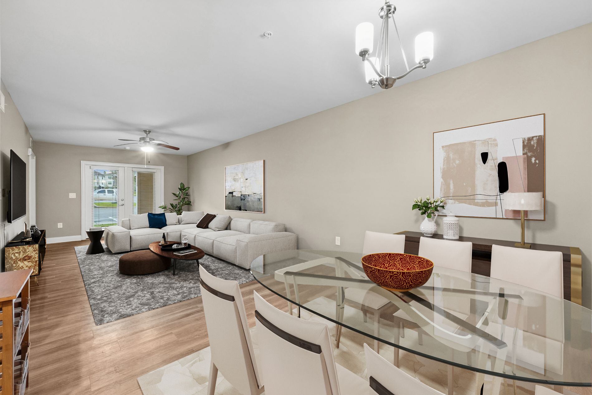 A modern living room with a glass dining table and white chairs.