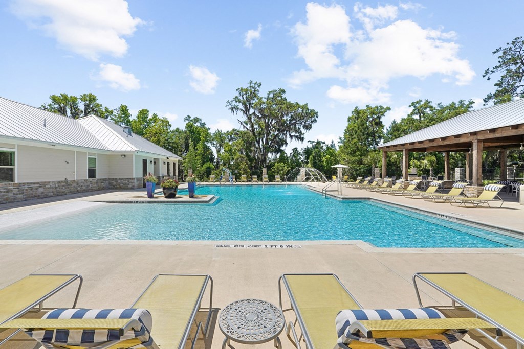 Sparkling swimming pool with lounge chairs at Capital Grand Apartments in Tallahassee, FL
