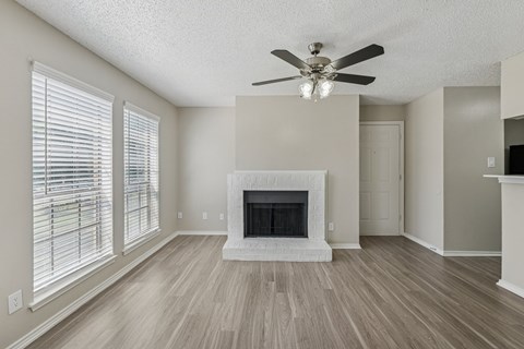 A living room with a fireplace and a ceiling fan.