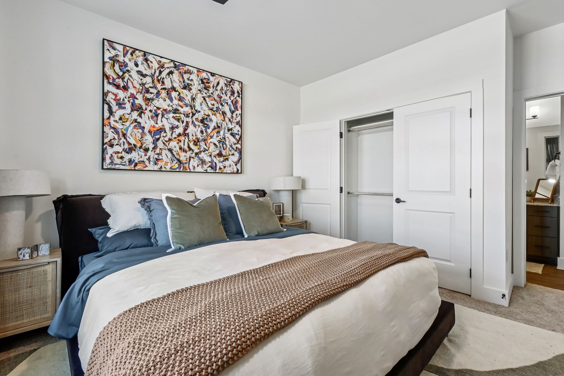 A bedroom with a large bed and a painting on the wall.