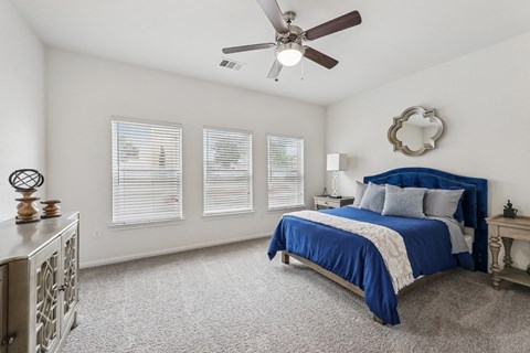 B3 carpeted bedroom bed, windows, and a ceiling fan at Creekside on Parmer Lane Apartments in Austin, TX