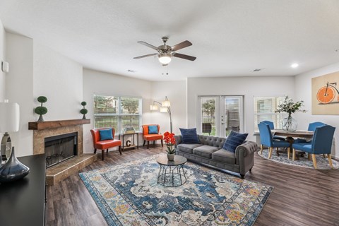 B3 living room with a couch, ceiling fan, windows, and a fireplace at Creekside on Parmer Lane Apartments in Austin, TX