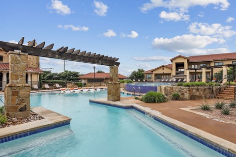 A swimming pool surrounded by lounge chairs at Creekside on Parmer Lane Apartments in Austin, TX