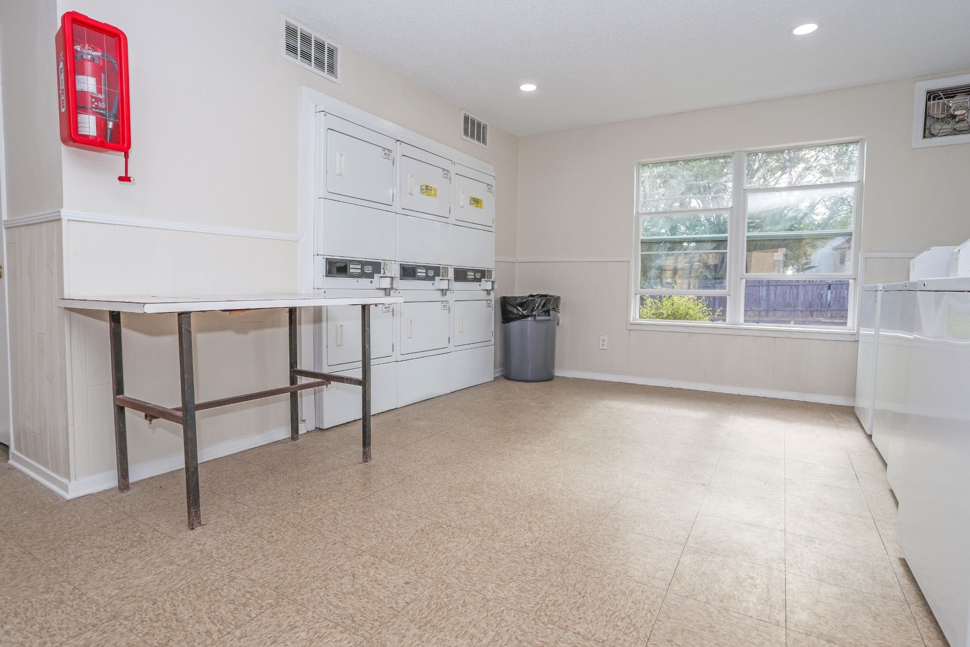 A kitchen with white cabinets and a red fire extinguisher on the wall.