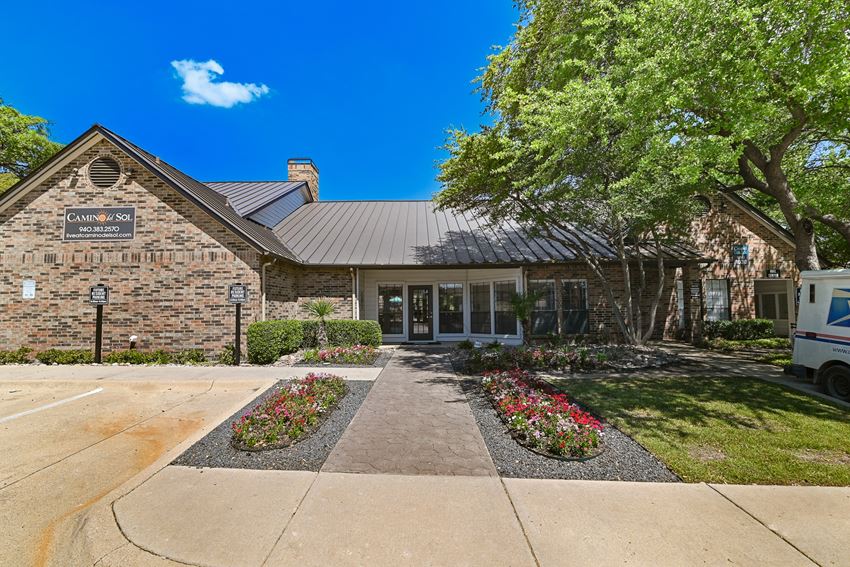 a view of the front of the building with a tree and flowers in front of it