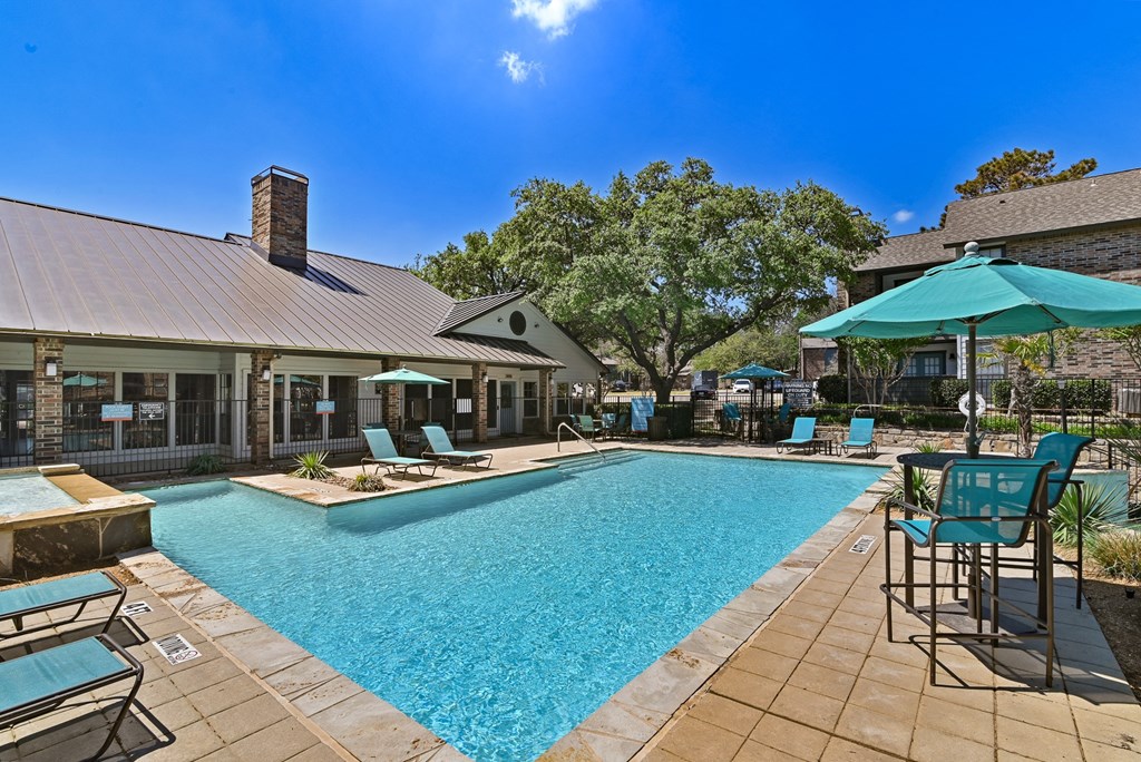 a pool with lounge chairs and umbrellas at the enclave at woodbridge apartments in sugar