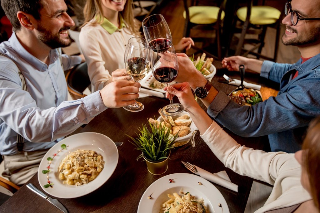 A group of people toasting with wine glasses at a dinner table.