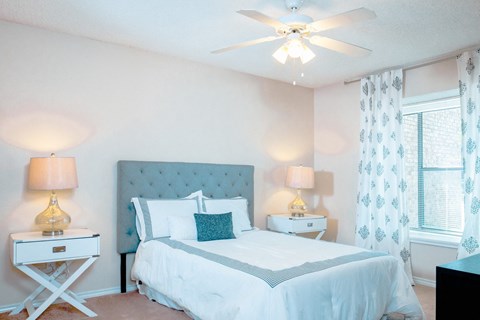 Model bedroom with a bed and a ceiling fan at Chisholm Place Apartments in Plano, TX