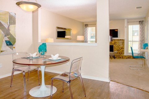 Dining room with a table and chairs and living room at Chisholm Place Apartments in Plano, TX