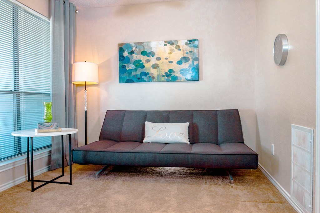 Model bedroom/den with a couch and a painting at Chisholm Place Apartments in Plano, TX