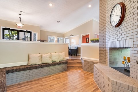 a living room with a brick fireplace and a clock on the wall
