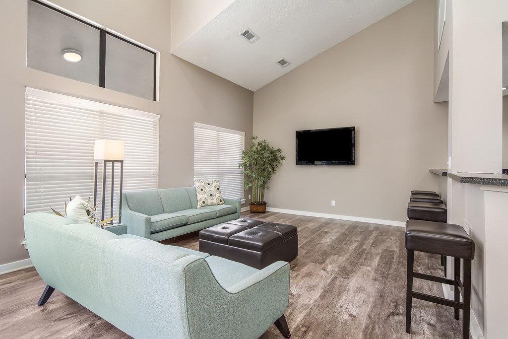 Clubhouse with a green couch and a flat screen TV mounted on the wall at Poplar Place Apartments