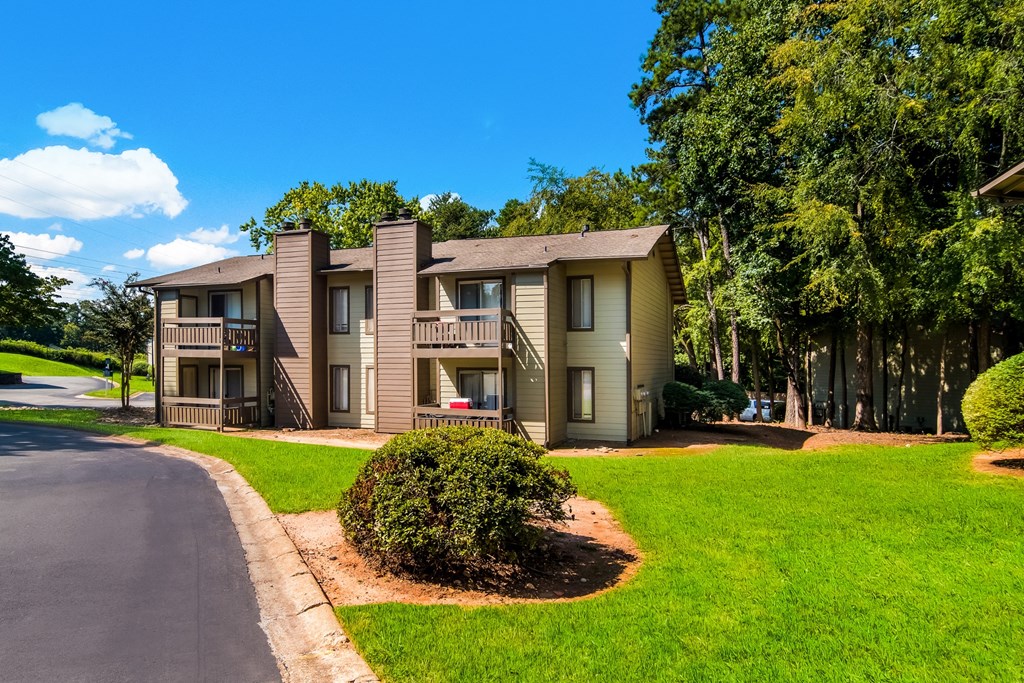 our apartments are located on the corner of a street with trees and grass