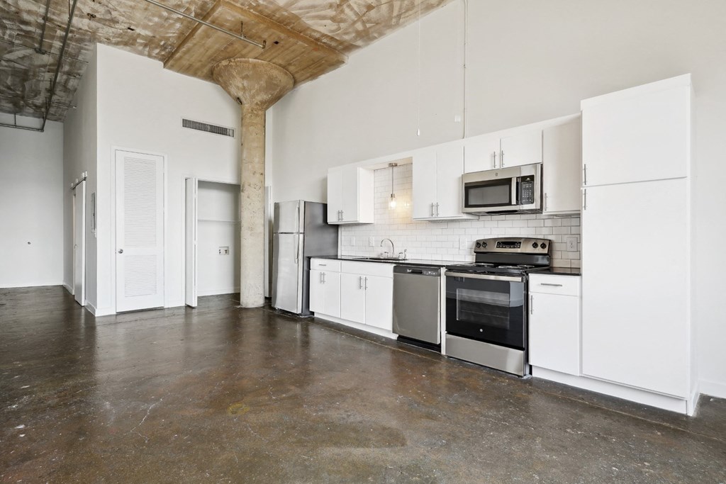Continental Building loft kitchen with stainless steel appliances and white cabinets | Continental Lofts Building from Deep Ellum Lofts in Dallas, TX