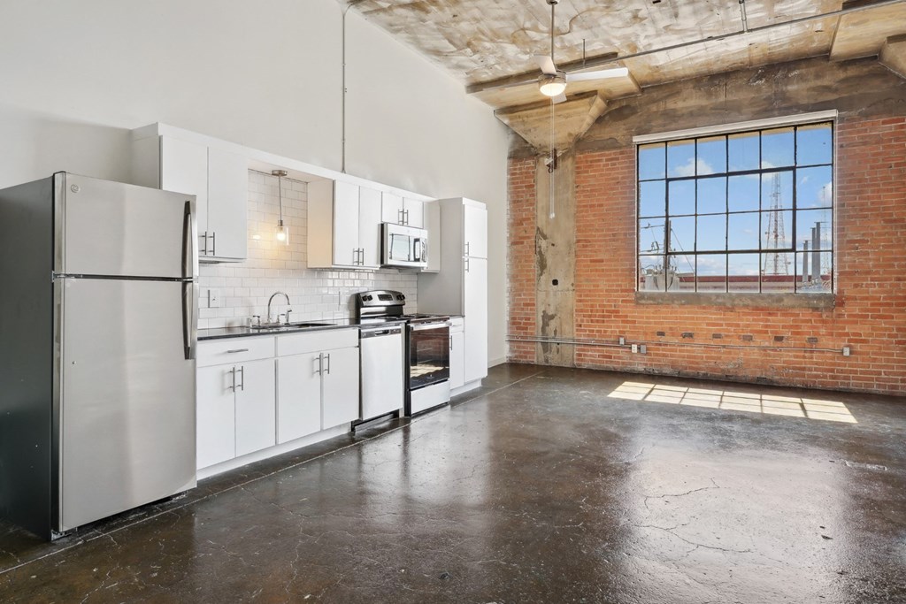 Kitchen from loft with brick wall, white cabinetry, and stainless steel appliances | Continental Building Lofts from Deep Ellum Lofts in Dallas, TX