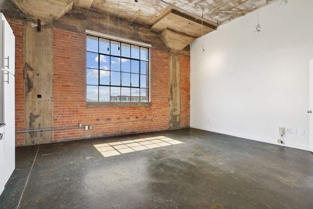 Living area in loft at Continental Lofts with brick wall and large window as well as polished concrete floor | Continental Building Lofts from Deep Ellum Lofts in Dallas, TX