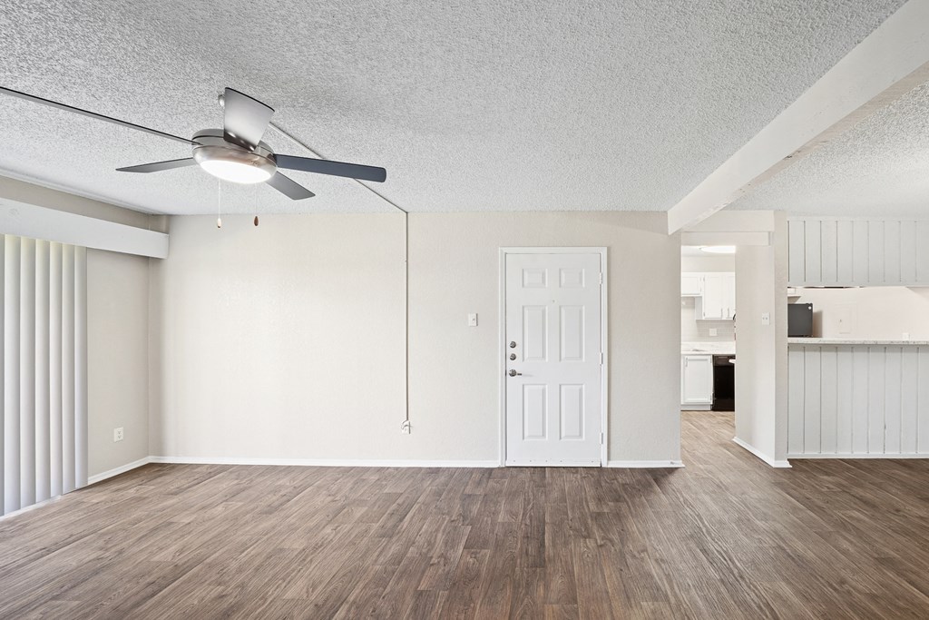 an empty living room with a ceiling fan