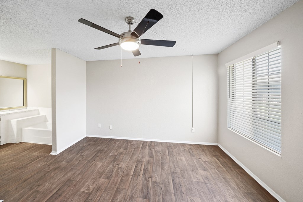 an empty living room with a ceiling fan