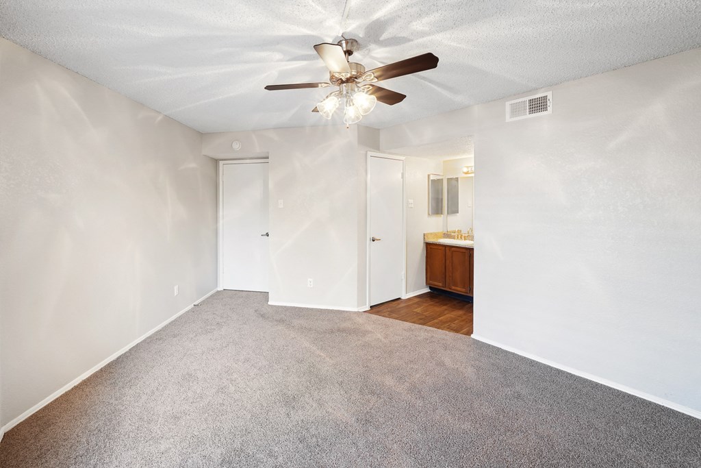 a bedroom with white walls and a ceiling fan