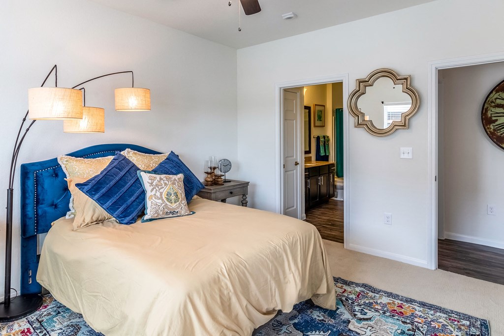 a bedroom with a bed and two lamps and a doorway to a bathroom