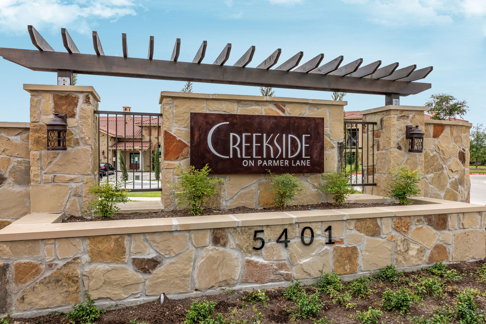 a stone retaining wall with a sign for creekside on paradise lane