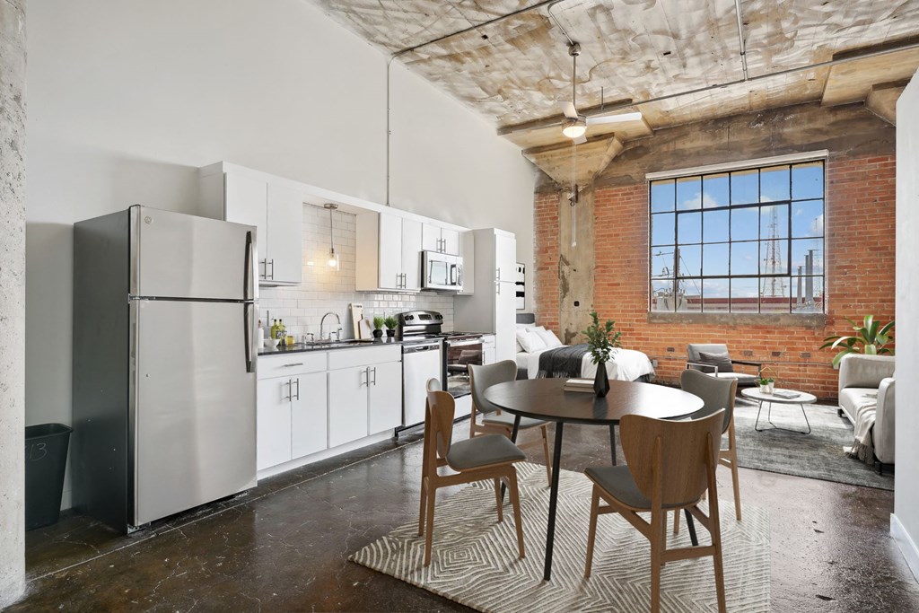 Deep Ellum Lofts Continental building virtually staged loft kitchen and living area with stainless steel appliances and brick accent wall | Deep Ellum Lofts in Dallas, TX