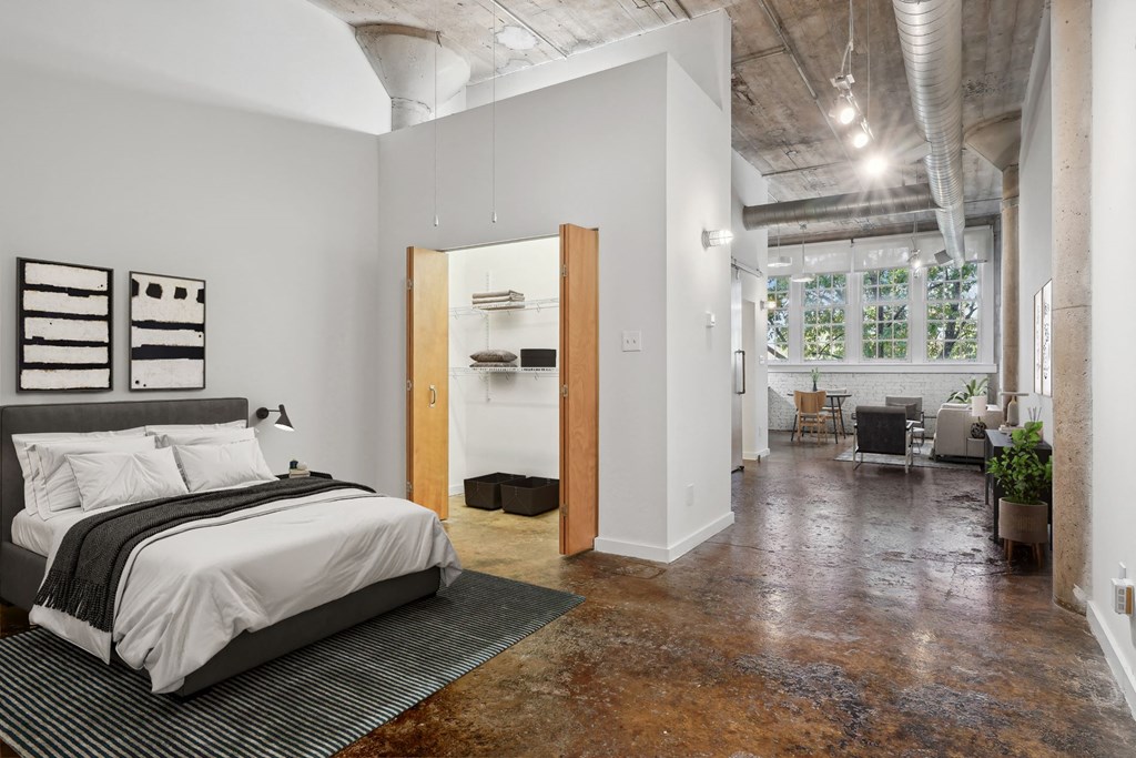 Futura Lofts virtually staged bedroom space with large closet and hall leading to kitchen and living area | Deep Ellum Lofts in Dallas, TX