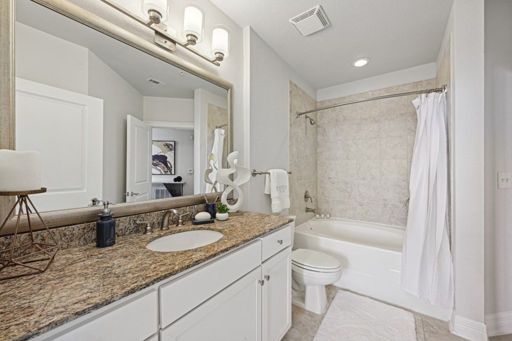 Model bathroom with granite countertop and jacuzzi tub at Dominion Post Oak apartments in Houston, TX
