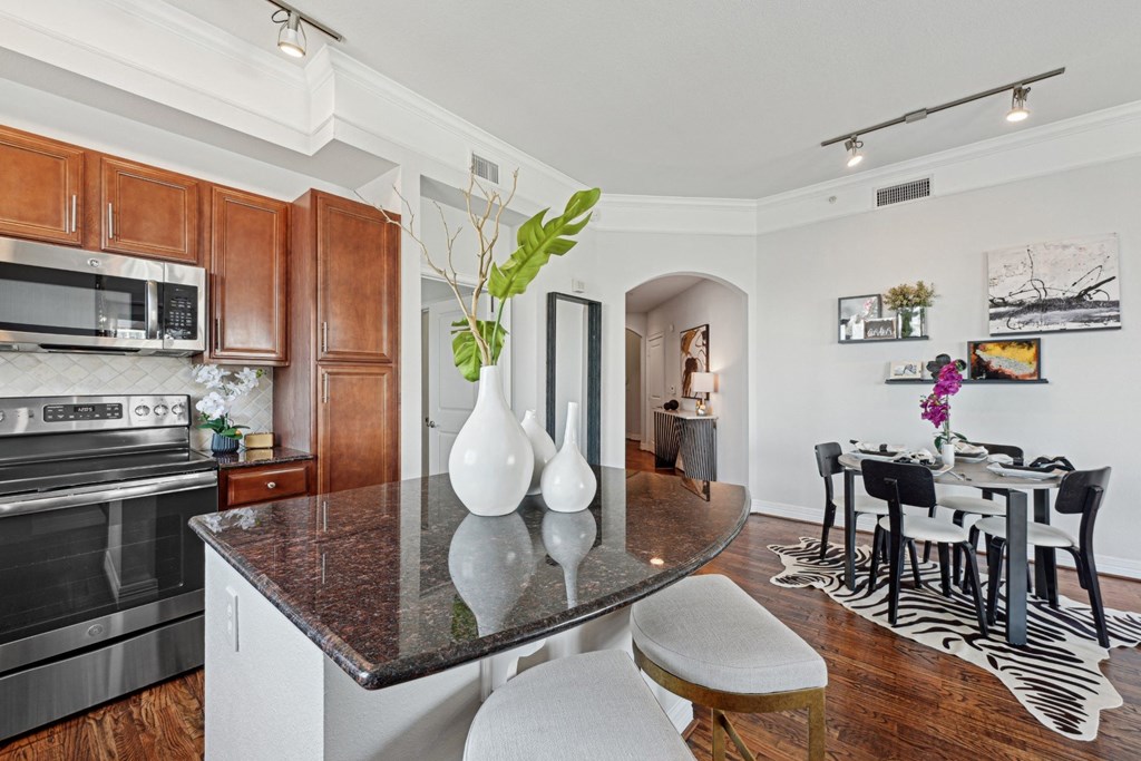 A kitchen with a black granite countertop and maple colored cabinets at Dominion Post Oak apartments in Houston, TX