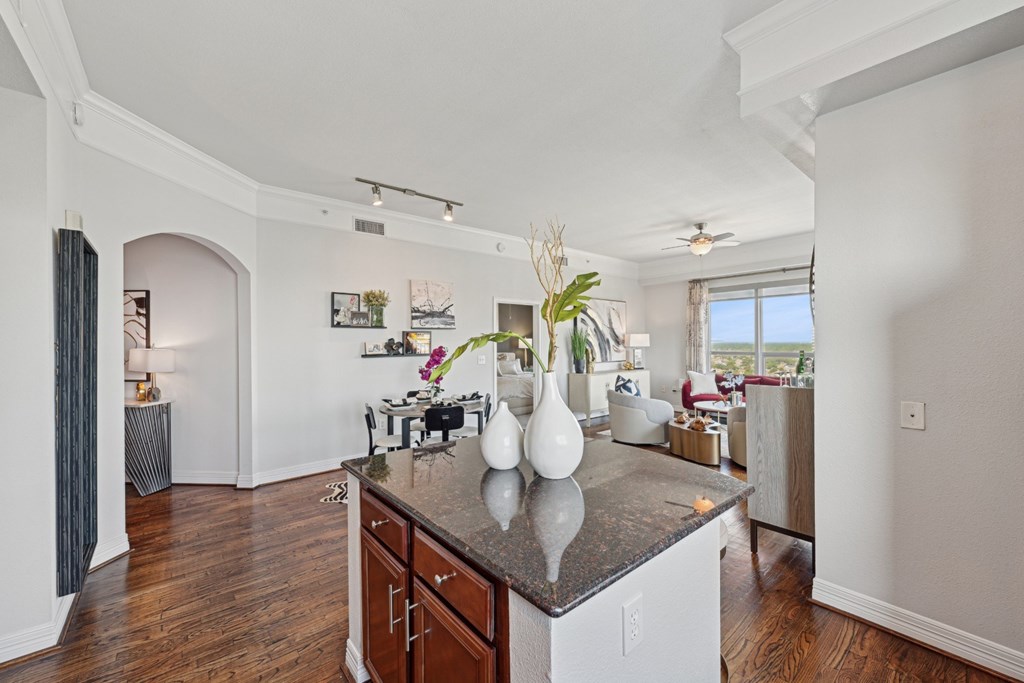 Model kitchen with a dark counter top and wooden floors at Dominion Post Oak apartments in Houston, TX