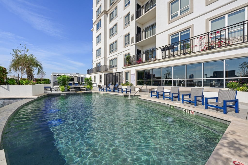 Our swimming pool in on the rooftop patio with blue chairs around it at Dominion Post Oak apartments in Houston, TX