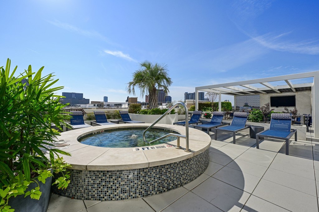 Rooftop pool with a hot tub with blue chairs and a white awning at Dominion Post Oak apartments in Houston, TX