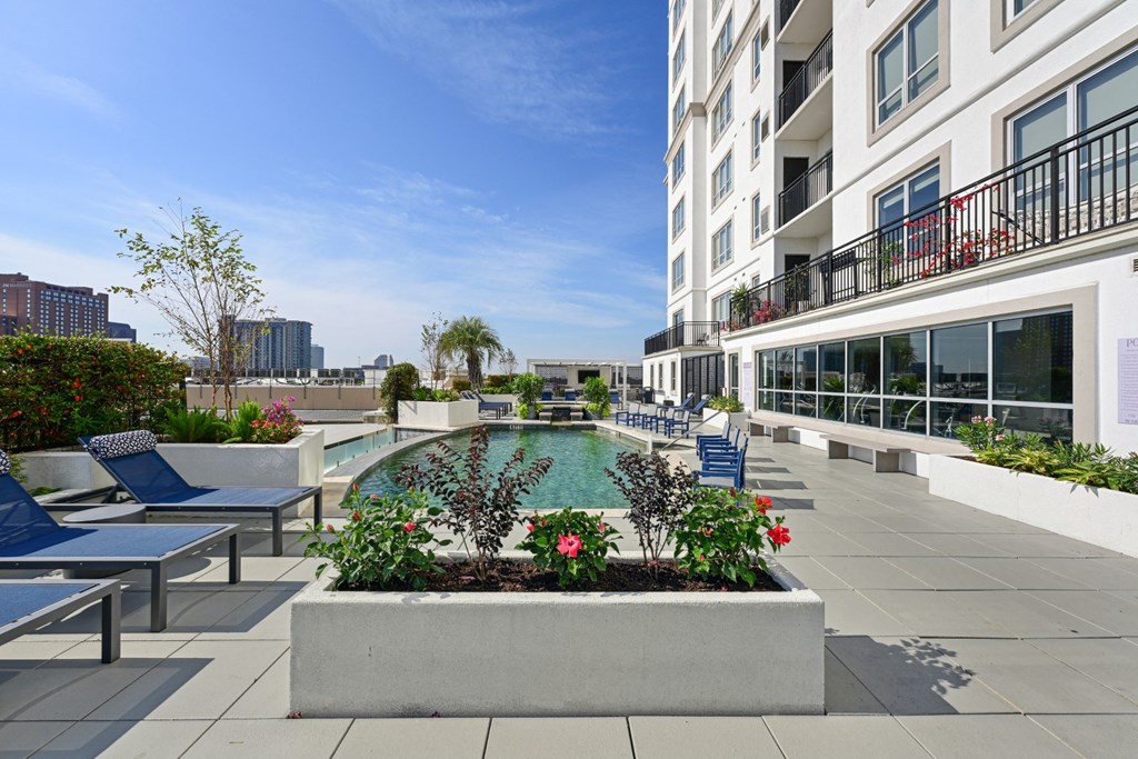 Our rooftop pool with a planter box with flowers and chairs at Dominion Post Oak apartments in Houston, TX