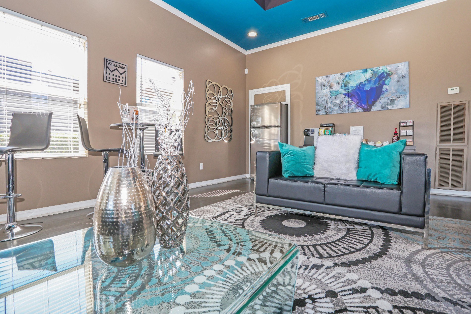 A living room with a grey couch and a large painting on the wall.
