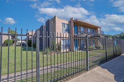 A modern apartment building with a black fence in front at The Drake in Bossier City, LA