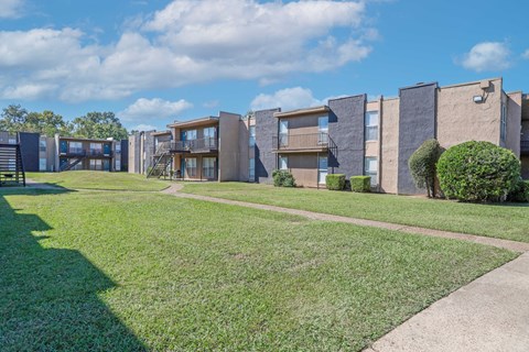 A row of modern apartment buildings with a green lawn in front at The Drake in Bossier City, LA