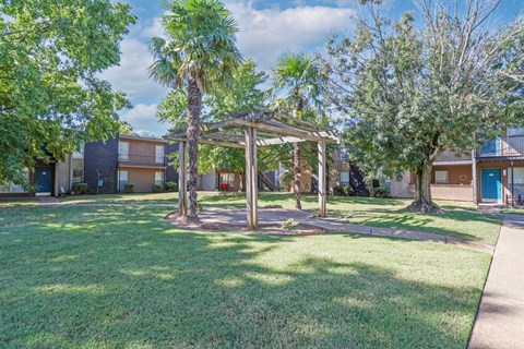 A gazebo and trees in a clearing with apartment buildings in the background at The Drake in Bossier City, LA