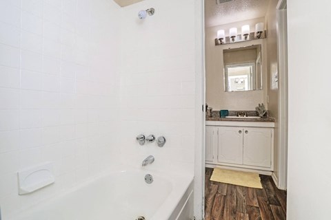 A white bathroom with a tub and a mirror at The Drake in Bossier City, LA