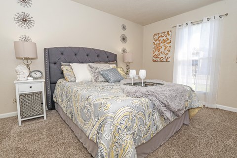 A bedroom with a bed, nightstand, and wall decorations at The Drake in Bossier City, LA